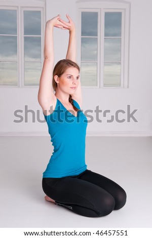 Young woman is doing some meditation in a white room