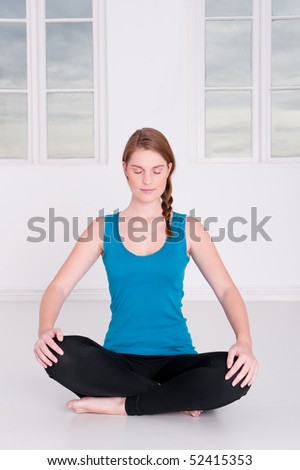 Young woman is doing some meditation in a white room