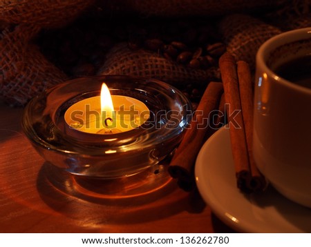 night background with a cup of coffee, candles, cinnamon and coffee beans