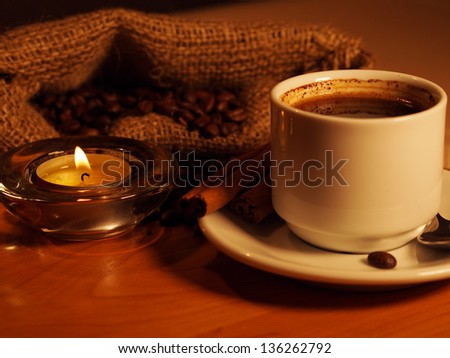 night background with a cup of coffee, candles and coffee beans