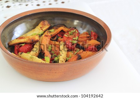 Roasted winter vegetables, in serving bowl. Including carrots and parsnip, Garnished with lemon balm.