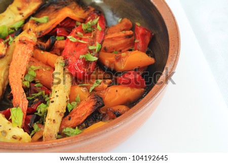 Roasted winter vegetables, in serving bowl. Including carrots and parsnip, Garnished with lemon balm.