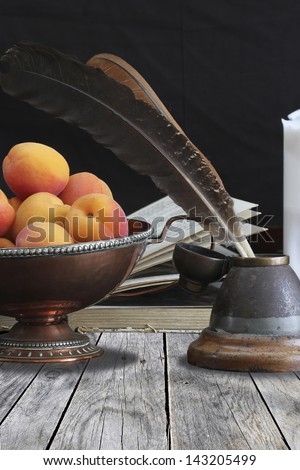 Still life of ink stand, book, feather and candle