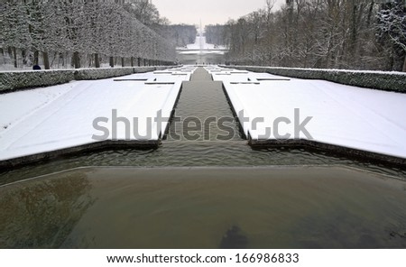 Perspective of ponds under the snow, a winter in a park in France