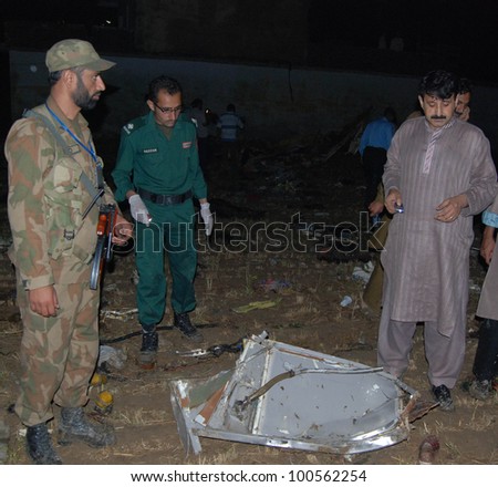 ISLAMABAD, PAKISTAN - APR 20: A soldier and rescue workers observe a piece of wreckage of the plane that crashed near Islamabad, Pakistan that killed 127 passengers April 20, 2012 in Islamabad