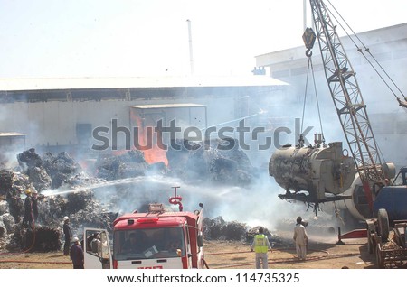 KARACHI, PAKISTAN - OCT 05: Fire fighters extinguish fire that broke out in cotton  warehouse located in the tissue paper manufacturing factory due to unknown reasons  on October 05, 2012 in Karachi.