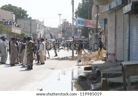 KARACHI, PAKISTAN - NOV 26: People and security officials gather at site after bomb blast at precast bricks depot in Malir area on November 26, 2012 In Karachi.