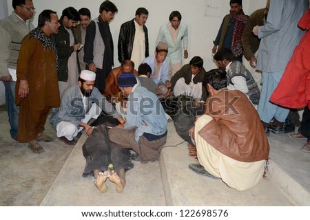 QUETTA, PAKISTAN - DEC 24: People gather near dead bodies of firing victims after  firing by unidentified gunmen on police check post at Eastern Bypass near Bosa Mandi,on December 24, 2012 in Quetta.