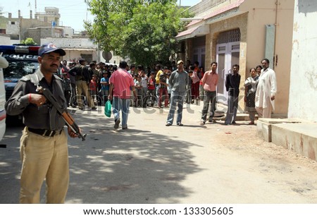 KARACHI, PAKISTAN - MAR 28: Police officials and people gather at the site after bomb  explosion at Landhi area on March 28, 2013 in Karachi. At least two people were injured in a bomb explosion.