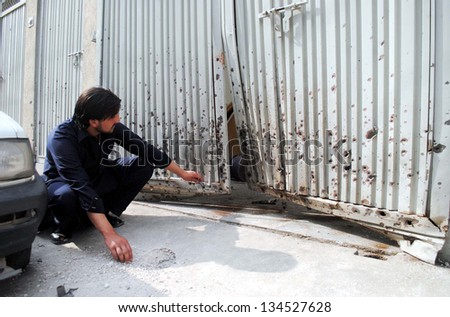 PESHAWAR, PAKISTAN - APR 09: A youth looks damaged gate of house after mortar bombs explosion at Hayatabad area on April 09, 2013 in Peshawar. Militants fired five mortar bombs.
