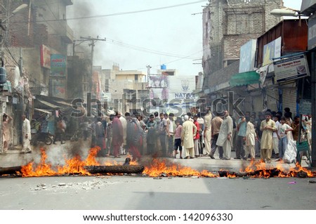 LAHORE, PAKISTAN - JUN 13: Residents of Nadeem Shaheed road block road burn tyres and bushes as they are protesting against electricity load shedding in their area on June 13, 2013 in Lahore.