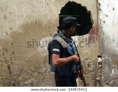 KARACHI, PAKISTAN - JUL 05: Security officials cordon off Hingora Abad area after the clash between two armed groups, in Lyari on July 05, 2013 in Karachi.