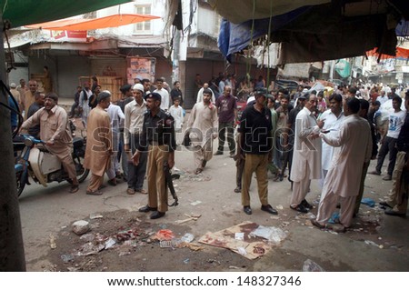 KARACHI, PAKISTAN - AUG 01: Police officials and people gather at site after firing incident at Jodia Bazar on August 01, 2013 in Karachi. At least three people were shot dead.