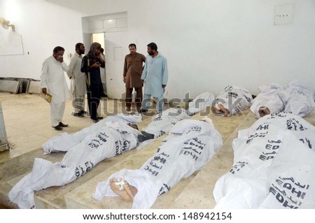 QUETTA, PAKISTAN - AUG 06: People gather near dead bodies of passengers, who killed unknown armed assailants at Giyani Pul on August 06, 2013 in Quetta. At least thirteen people shot dead