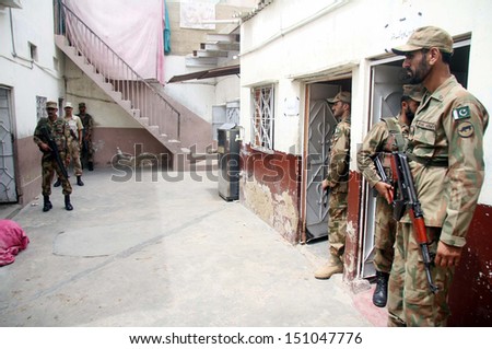 KARACHI, PAKISTAN - AUG 22: Security officials stand alert to avoid untoward incidents at a polling station during by-election for PS-95 at Orangi area on August 22, 2013 in Karachi.
