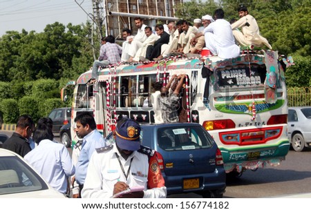 KARACHI, PAKISTAN - OCT 03: Passengers travelling on an overloaded bus as the short of public transport is being observed due to closure of CNG Stations, on October 03, 2013 in Karachi.