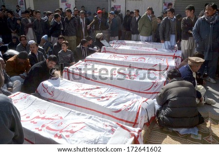 QUETTA, PAKISTAN - JAN 22: Shiite Muslims sit along with dead bodies that were killed in suicide bomb blast near Shia pilgrims bus in Mastung,  on January 22, 2014 in Quetta.