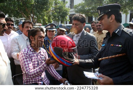 LAHORE, PAKISTAN - OCT 20: Traffic Police officer distributing helmet among motorcycle riders during Ride Safely awareness campaign, held at Mall Road on  October 20, 2014 in Lahore.