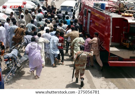 KARACHI, PAKISTAN - MAY 04: Rescue and people gather near a burning garments factory building while heavy smoke fire flame rises from burning goods after fire broken  on May 04, 2015 in Karachi.