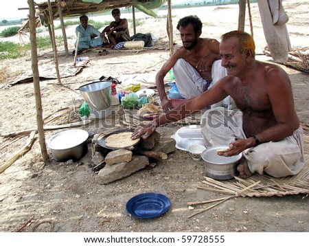 HYDERABAD, PAKISTAN - AUG 7: Flood affected people prep food near a bank of  the Indus River on August 7, 2010 in Suresh Nagar, Hyderabad. (Aftab  Ahmed/PPI Photo)