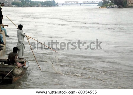 SUKKUR, PAKISTAN - AUG 28: A fisherman catch fishes through a net at a bank of Indus River on August 28, 2010 in Sukkur.