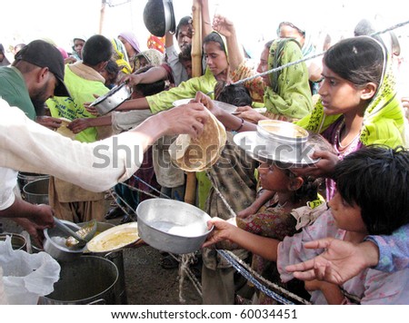 HYDERABAD, PAKISTAN - AUG 28: Flood affected women receive food during distribution of food at a relief camp on August 28, 2010 in Hyderabad.