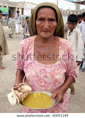 HYDERABAD, PAKISTAN - AUG 30: A flood-affected aged woman carries food during food distribution at a flood-affectees relief camp on August 30, 2010 in Hyderabad.