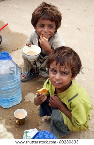 KARACHI, PAKISTAN-AUG 31: Flood affected children eat snack with tea at flood relief camp established at Razzaqabad area in Karachi on Tuesday, August 31, 2010. (Rizwan Ali/PPI Images).