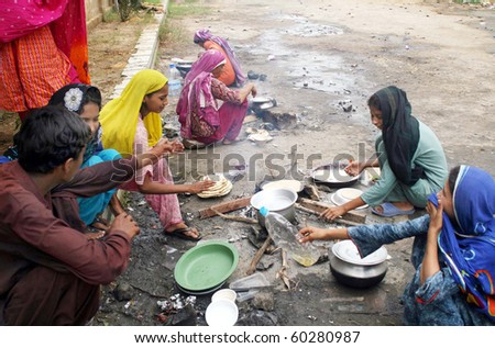 KARACHI, PAKISTAN-AUG 31: Flood affected women prepare food for their families at flood relief camp established at Razzaqabad area on Tuesday  August 31, 2010 in Karachi