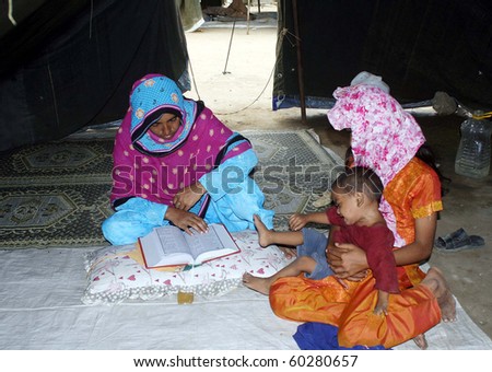 KARACHI, PAKISTAN-AUG 31: Flood affected woman recites Holy Quran at makeshift tent house at flood relief camp established at Razzaqabad area during the Holy month of Ramadan Aug 31, 2010 in Karachi