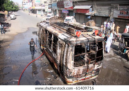 KARACHI, PAKISTAN- SEPT 17: People gather near burnt vehicle at Burns Road in Karachi, Pakistan on Sept. 17, 2010, as violence erupts in city following the slaying in London of Muttehda Qaumi Movement Senior leader, Imran Farooq.