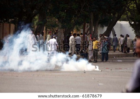 KARACHI- SEPT 24: Protesters run towards safe place after police officials fired tear gas shells to disperse them during protest demonstration of Islami Jamiat Talba Sept 24, 2010 in Karachi