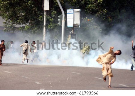 KARACHI- SEPT 24: Protesters run towards safe place after police officials fired tear gas shells to disperse them during protest demonstration of Islami Jamiat Talba Sept 24, 2010 in Karachi, Pakistan