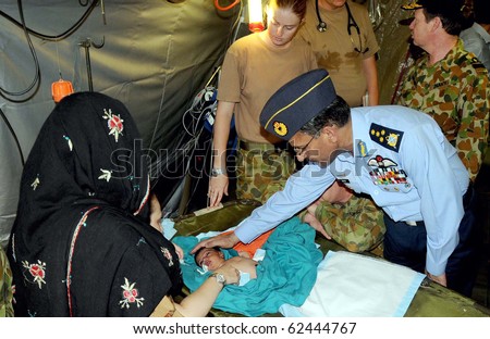KOT ADU, PAKISTAN, OCT 05: Air Chief Marshal Rao Qamar Suleman, Chief of the Army Staff Air Force (PAF) inquires about the health of infant child during his visits at forty bed mobile hospital on October 5, 2010 in Kot Adu, Pakistan