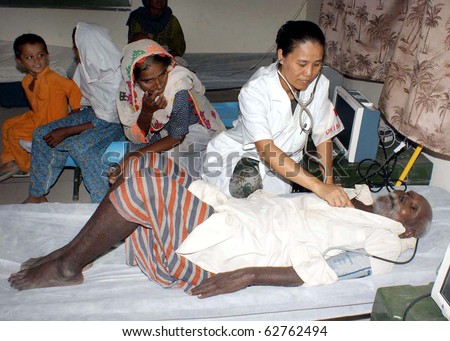 SEHWAN, PAKISTAN - OCT 09: Chinese doctor examines patients at free medical camp for flood affectees established by China Army on Saturday, October 09, 2010 in Sehwan, Pakistan