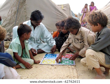 KARACHI, PAKISTAN - OCT 20: Flood affected Youth and children enjoy Ludo game at flood affectees relief camp on October 10, 2010 in Karachi, Pakistan
