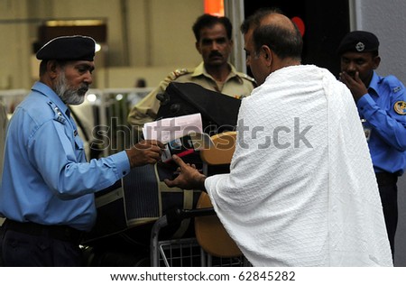 KARACHI, PAKISTAN - OCT 11: Airport security force (ASF) official checks travel documents of Pakistani Muslims before their departure for the Annual Hajj on October 11, 2010 in Karachi, Pakistan.
