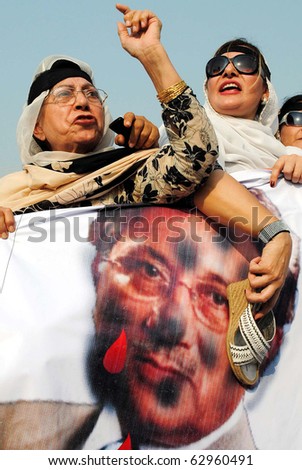PESHAWAR, PAKISTAN - OCT 12: Women activists of Muslim League-N beat poster of Pervez Musharraf during protest rally against the toppling of Nawaz Government, on October 12, 2010 in Peshawar.