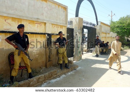 KARACHI, PAKISTAN - OCT 17: Police officials stand guard at a polling station at Orangi Town as security has been tightened during the by-election for PS-94, on October 17, 2010.