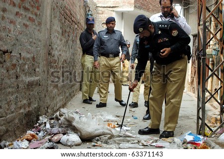 LAHORE, PAKISTAN - OCT 18: A police official examines the site of cracker blast on October 18, 2010 in Lahore.