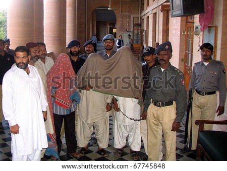KARACHI, PAKISTAN - DEC 23: Police officials escort three handcuffed accused (face covered with cloth) who were involved in Sher Shah scrap market massacre, on December 23, 2010.