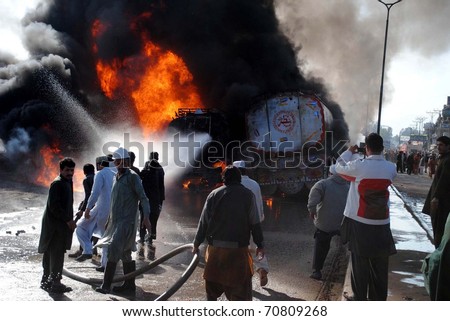 PESHAWAR, PAKISTAN - FEB 08: Fire fighters extinguish fire on burning oil-tankers and vehicles which were caught fire after attack by unknown miscreants on February 08, 2011in Peshawar .