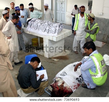 KARACHI, PAKISTAN - MAR 21: People gather near two dead bodies of accident victims who were lost their lifes in a road accident at National Highway at a hospital on  March 21, 2011 in Karachi.