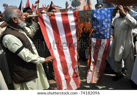 PESHAWAR, PAKISTAN - MAR 28: Activists of Railway Workers Union burn US flag as they are protesting against the desecration of the Holy Quran in US, on March 28, 2011 in Peshawar.