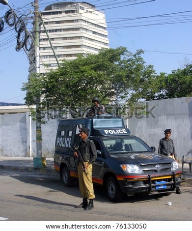 KARACHI, PAKISTAN - APR 27: Unidentified policemen stand guard at a road near Shaheen Complex building as security has been tightened in city after twin bomb attacks on April 27, 2011 in Karachi, Pakistan