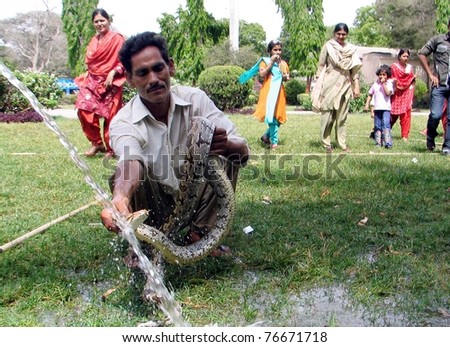 KARACHI, PAKISTAN - MAY 05: An Zoological Garden employee bathes a snake due to high summer season temperatures on May 05, 2011 in Karachi, Pakistan.