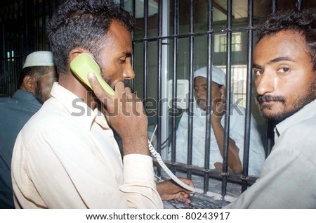 HYDERABAD, PAKISTAN - JUN 30: Prisoners talk on newly installed phones during meeting time central jail on June 30, 2011in Hyderabad, Pakistan.