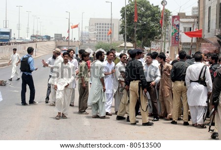 KARACHI, PAKISTAN - JUL 05: Policemen negotiate with angry mob who blocked road as violence erupts in the area after clash between two groups at Hasan Square on July 05, 2011in Karachi, Pakistan.