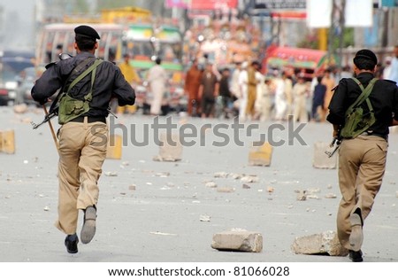 PESHAWAR, PAKISTAN - JULY 15: Policemen run towards angry mob to disperse them during protest demonstration of residents against prolonged electricity load-shedding on July 15, 2011 in Peshawar, Pakistan.