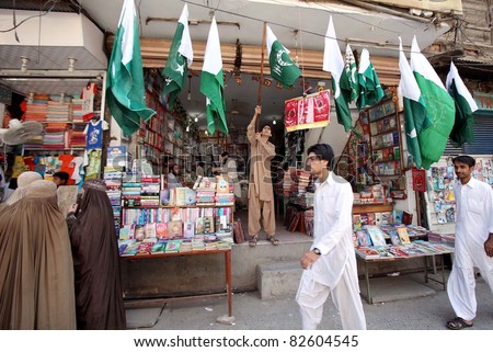 PESHAWAR, PAKISTAN - AUG 10: People pass through national flags displayed at a shop at Qissa Khawani Bazaar ahead of Independence Day celebrations on 10 August 2011in Peshawar.